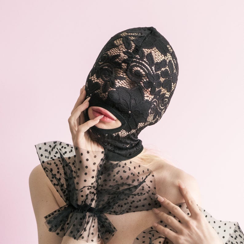 A handmade black full-face mask, only the mouth is visible. 67